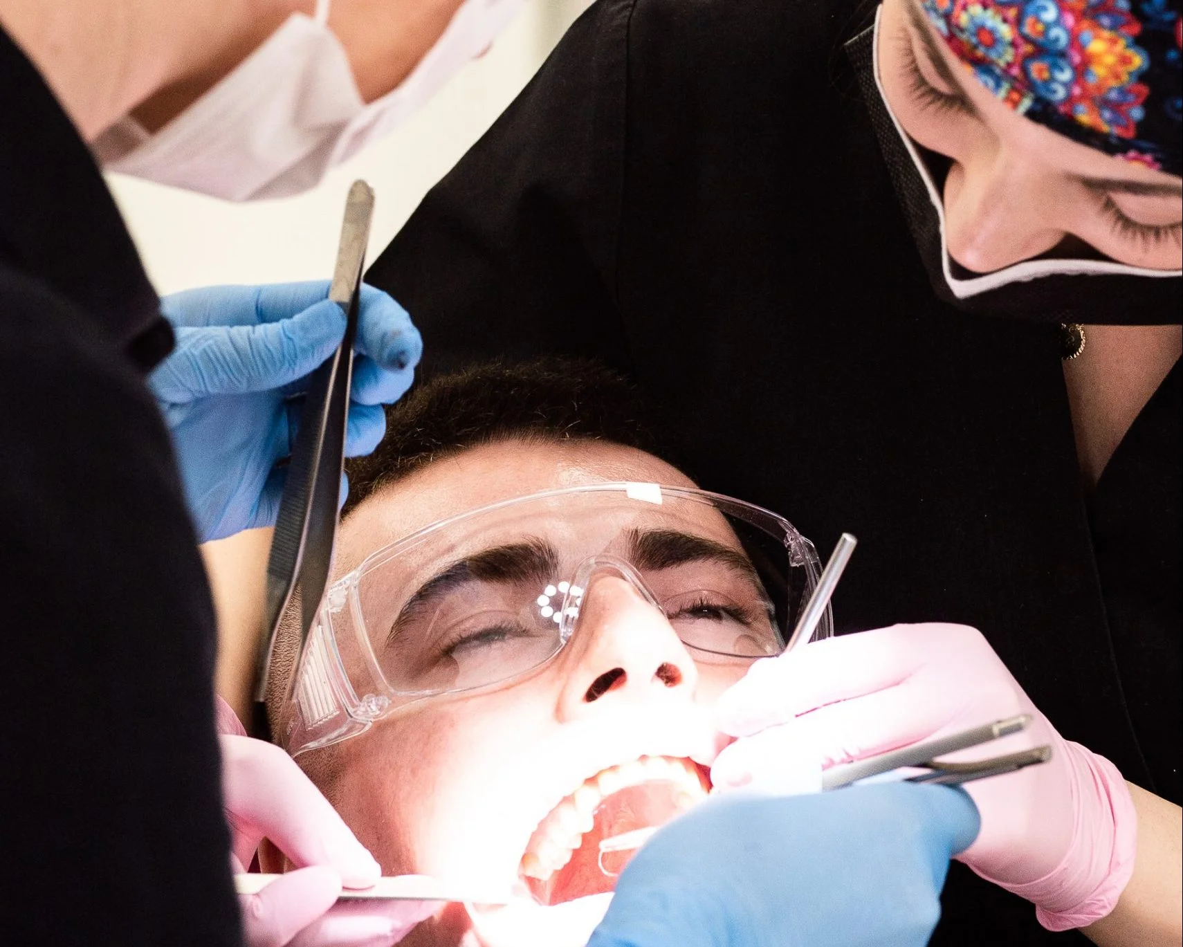 Pacient cu ochelari protecție, examinare dentară, mănuși colorate.